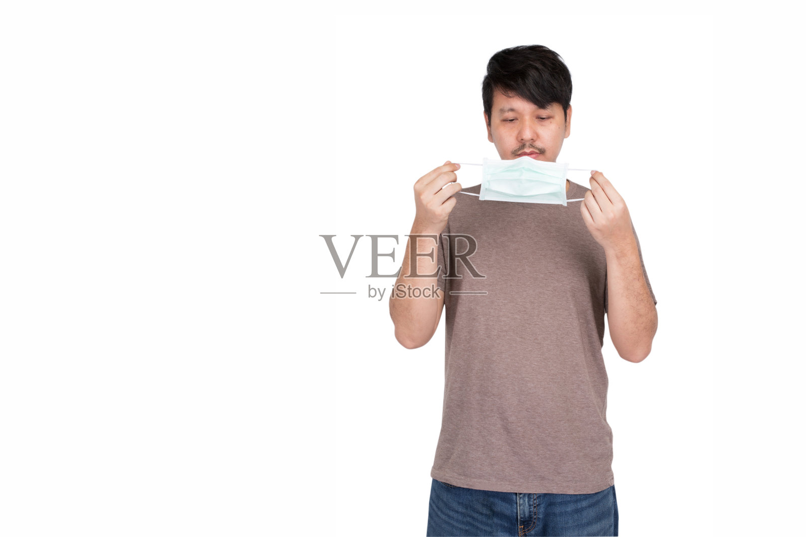 亚洲男子手持外科防护口罩，用双手准备戴口罩照片摄影图片