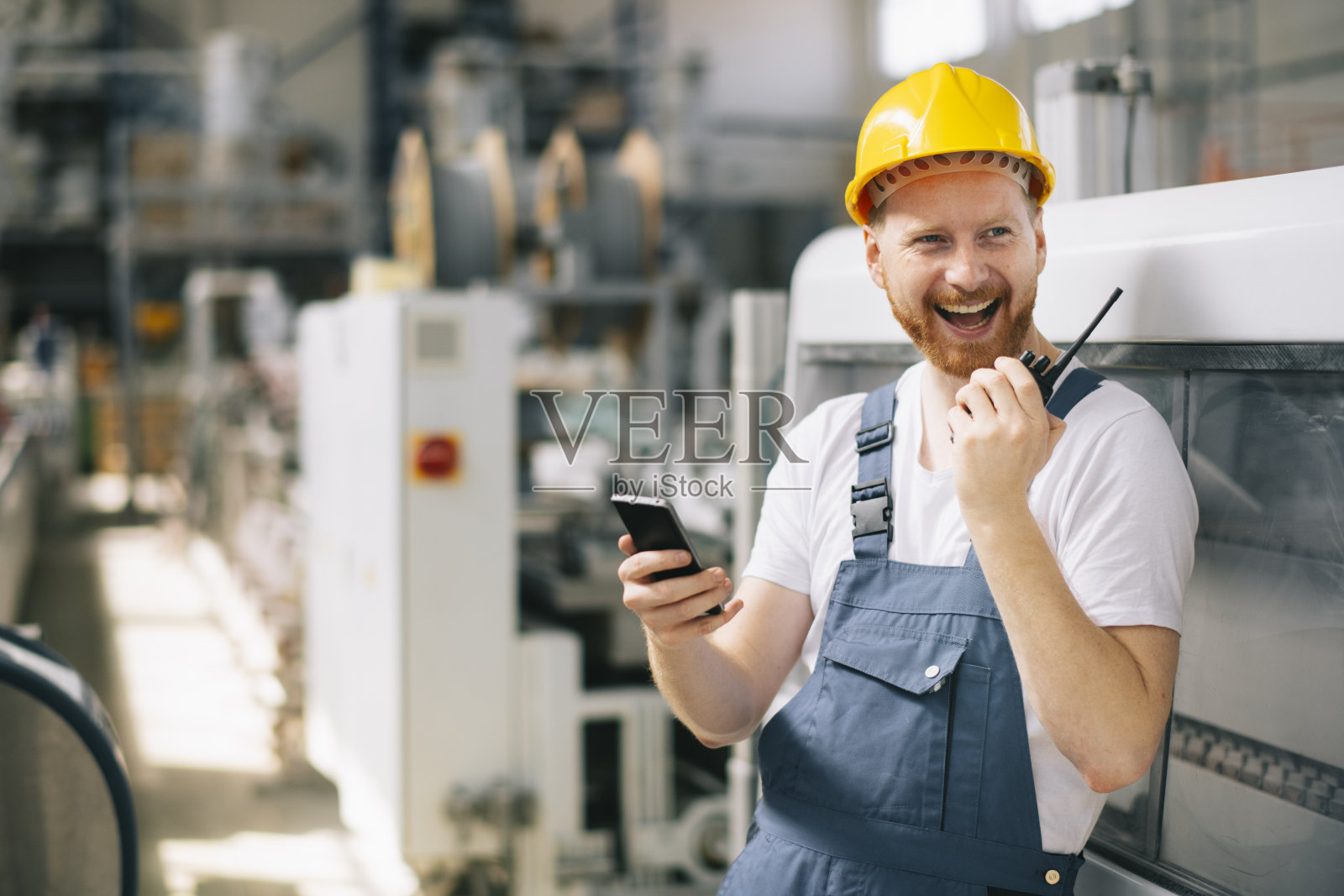 戴着头盔的年轻人在工厂工作。照片摄影图片