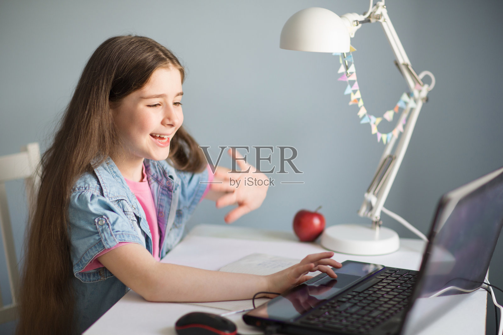 儿童学生在线学习与视频电话老师。快乐的小女孩远程学习。看着笔记本电脑，挥挥手。呆在家里。照片摄影图片
