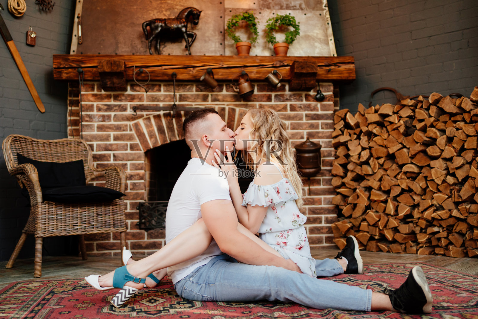 恋人坐在壁炉前的地毯上。照片摄影图片