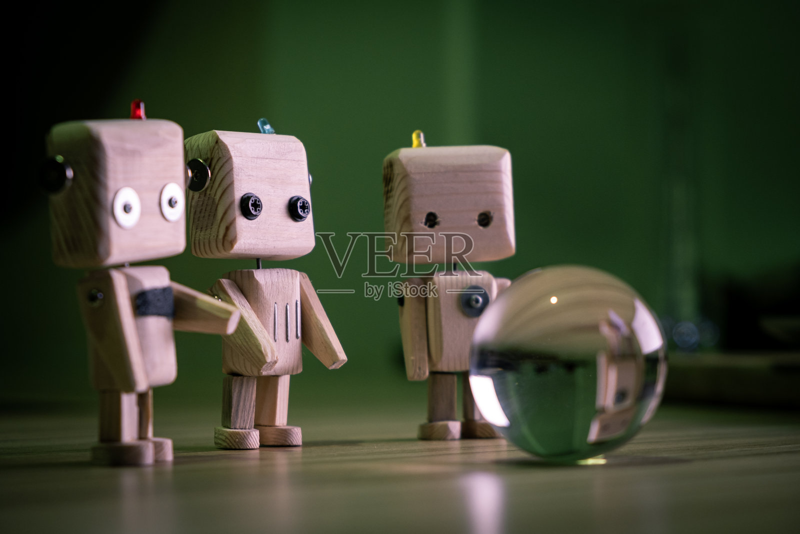一个小的木制玩具机器人在黑暗中看着一个玻璃球。墙纸,长途跋涉的背景。低光照片摄影图片