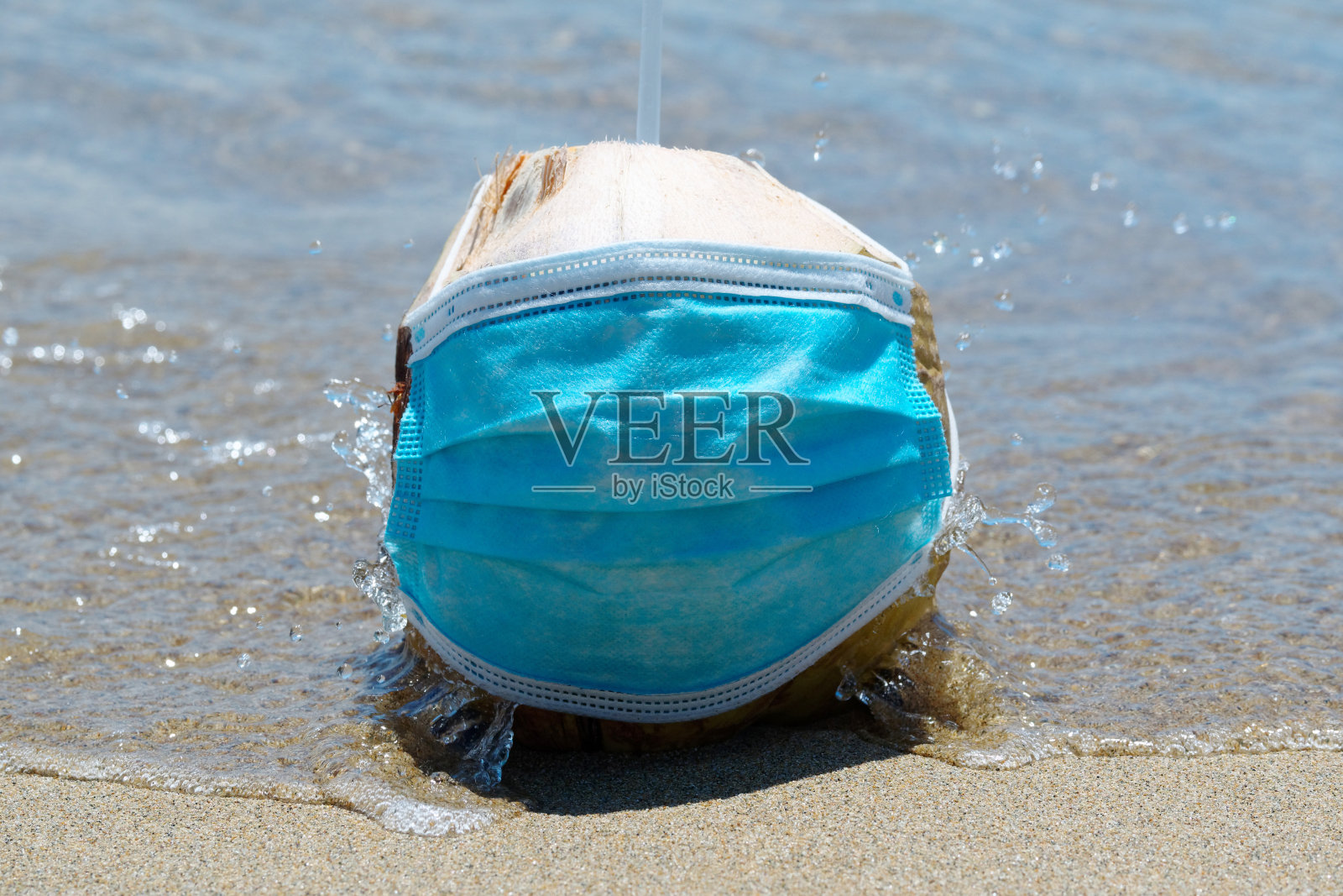 防毒面具和椰子鸡尾酒在沙滩上海浪。假期的概念。照片摄影图片