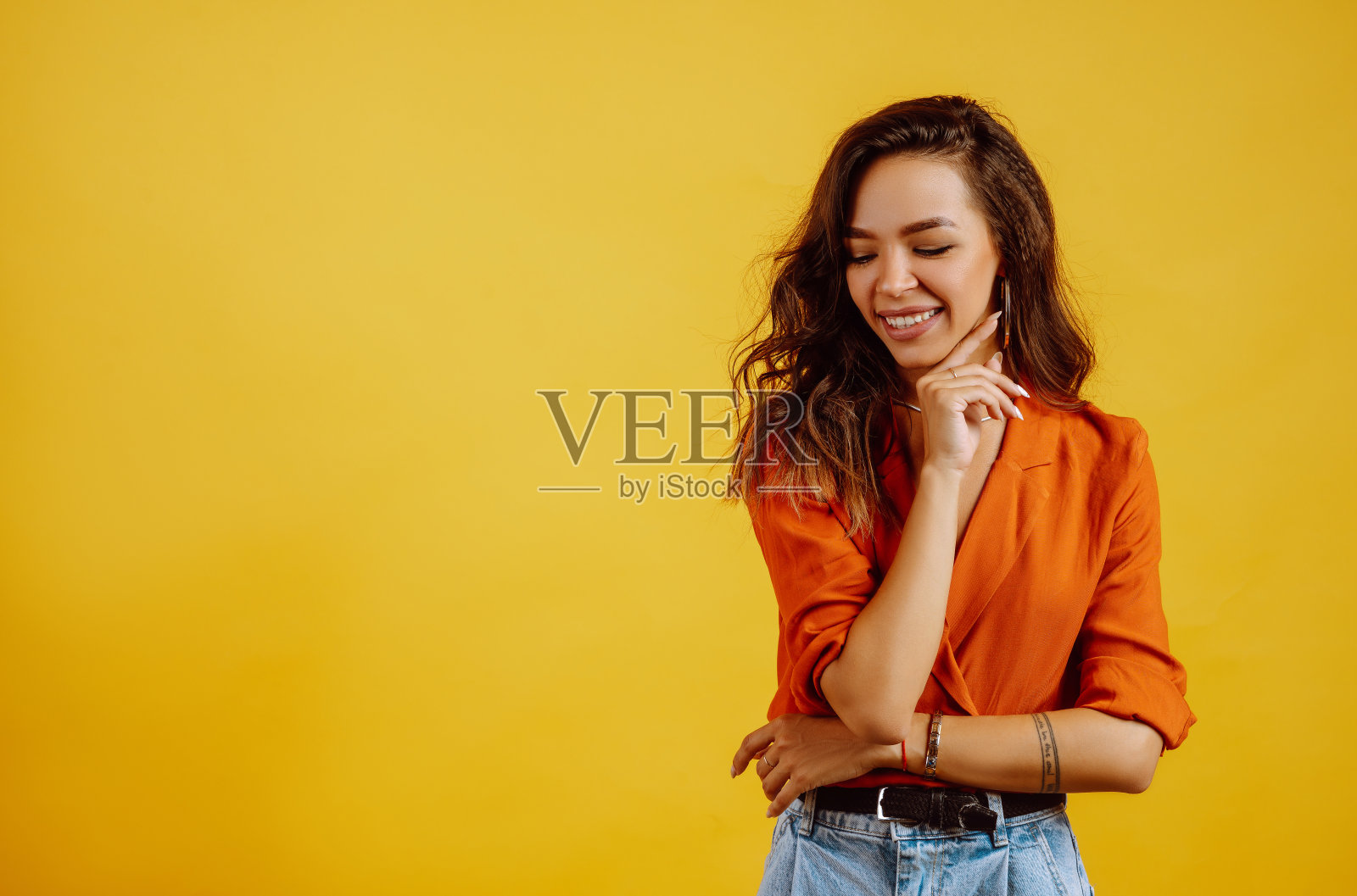 在黄色背景上摆姿势的年轻女孩的肖像。照片摄影图片