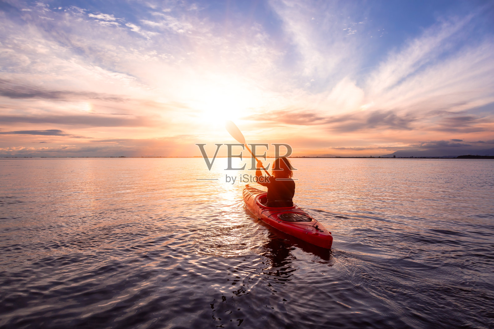 平静水域中的海上皮划艇，绚丽多彩的日落照片摄影图片