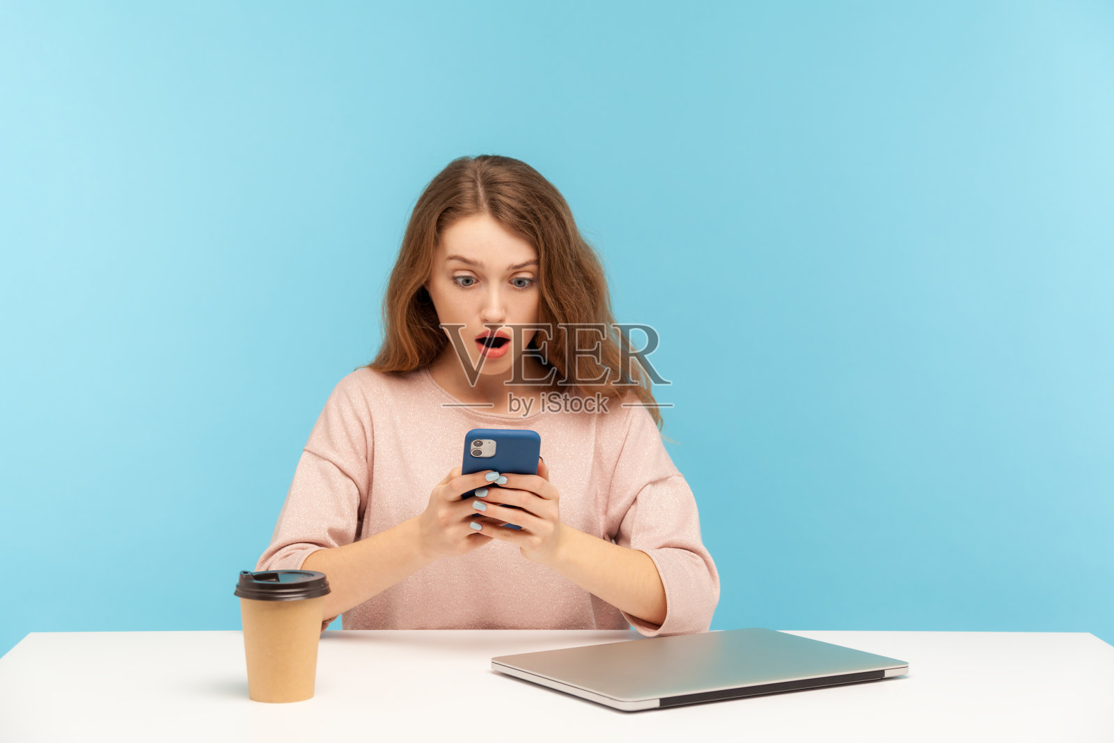 惊讶的年轻女子，办公室员工，在工作场所休息，关闭笔记本电脑和咖啡，阅读令人震惊的信息照片摄影图片