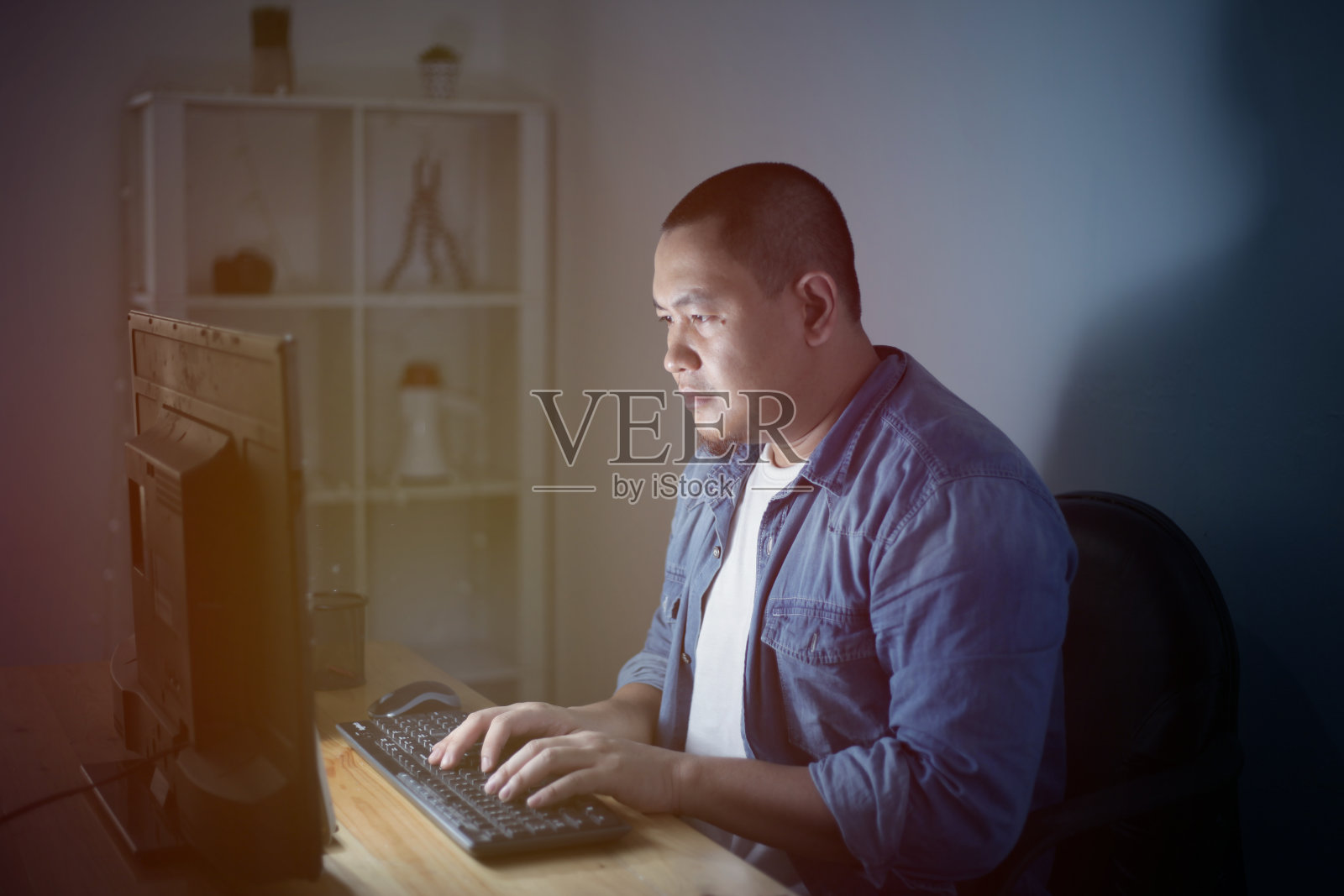 年轻的亚洲企业家独自在黑暗的办公室加班，为他的成功的野心努力工作照片摄影图片