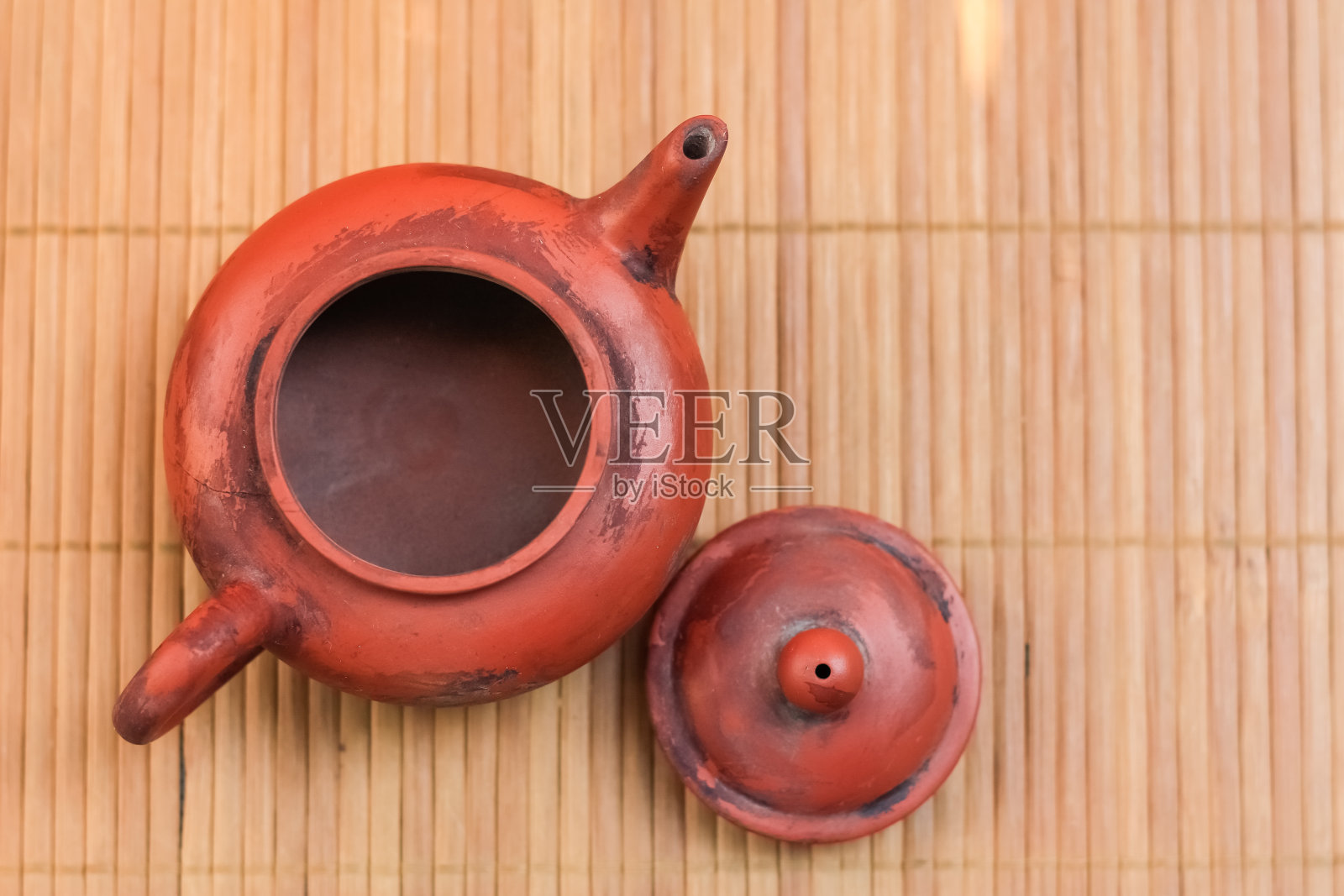 竹席上的旧棕色陶瓷茶壶。平放观。照片摄影图片