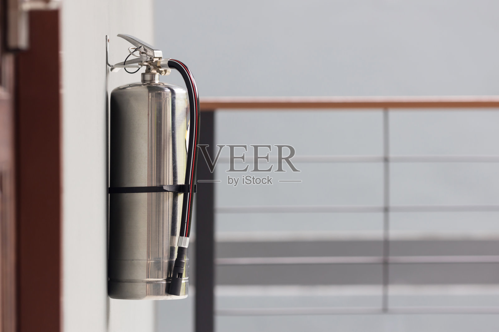 操作部门的灭火器。在建筑物的墙上安装一个灭火器。走廊内装有干粉灭火器，墙上挂有红色灭火器。照片摄影图片