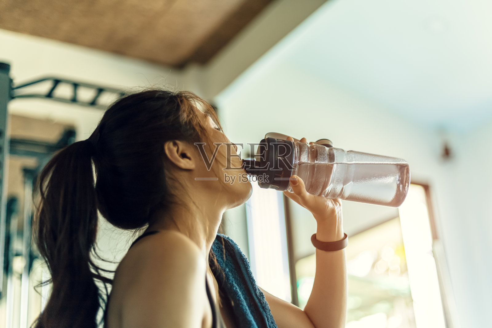 女人在健身房锻炼后休息和喝水。照片摄影图片