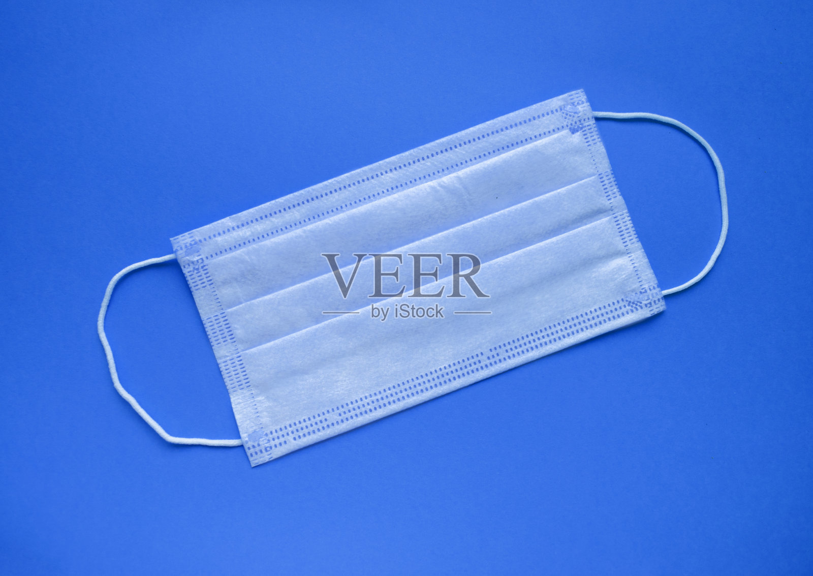 防护面罩平放。空气污染问题和感染预防。全球隔离期间的冠状病毒防护。蓝色背景上的面罩。照片摄影图片