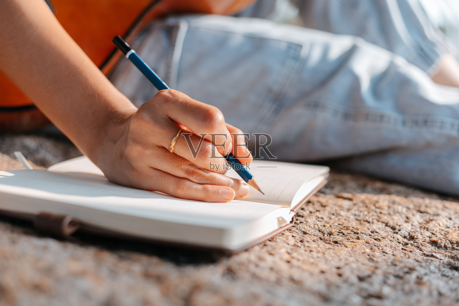 歌曲作者创作并写笔记，在公园的石头上写歌词。照片摄影图片