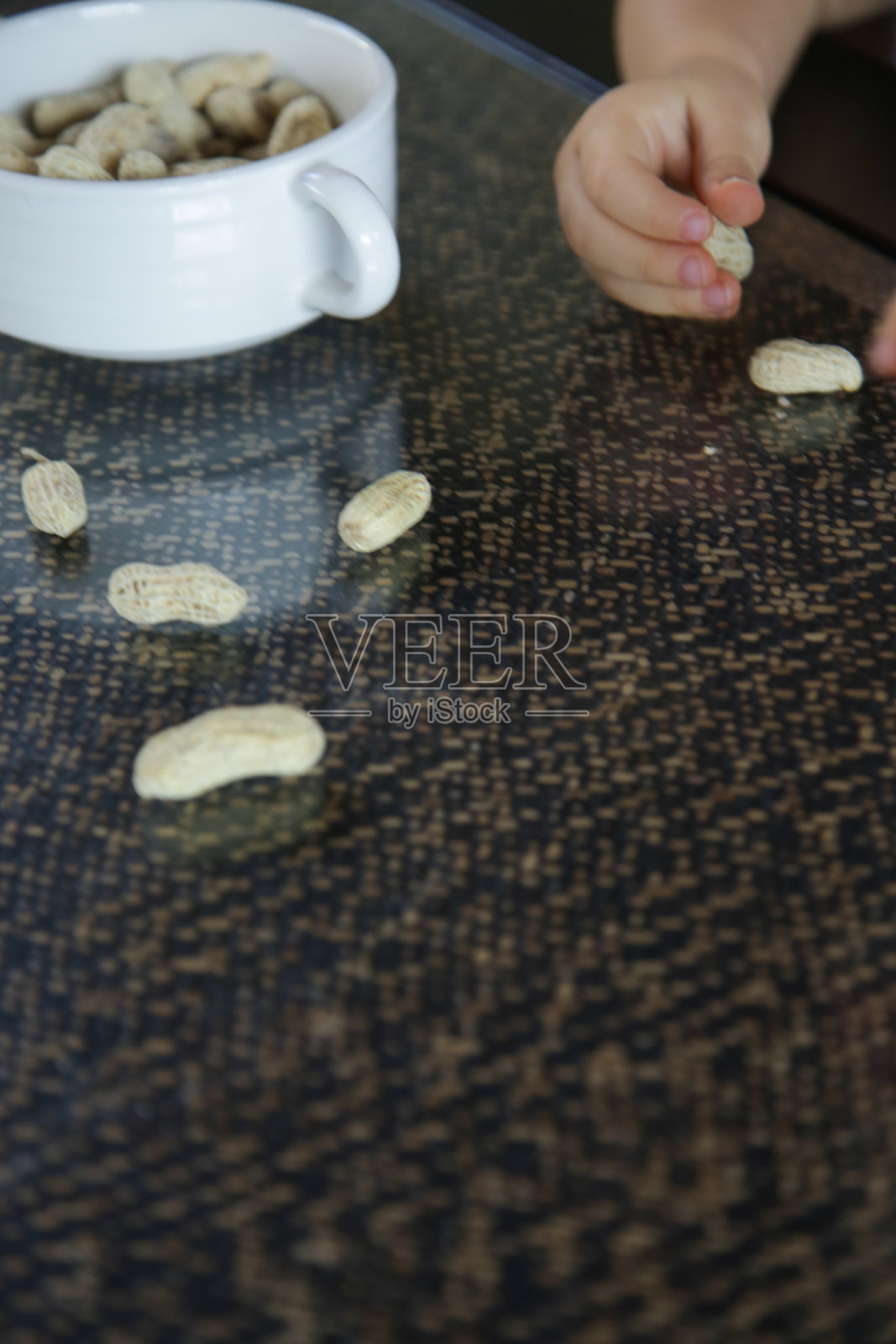 俯视图的孩子的手和花生壳在厨房的桌子上照片摄影图片