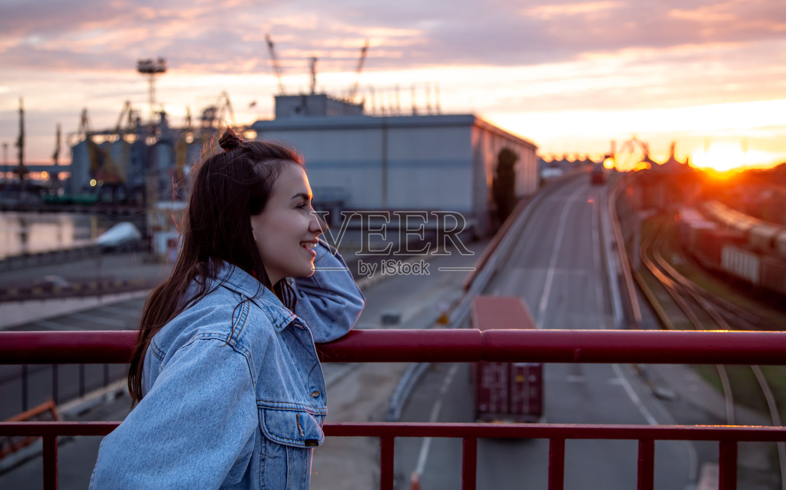 日落时分，桥上的一位年轻女子。照片摄影图片