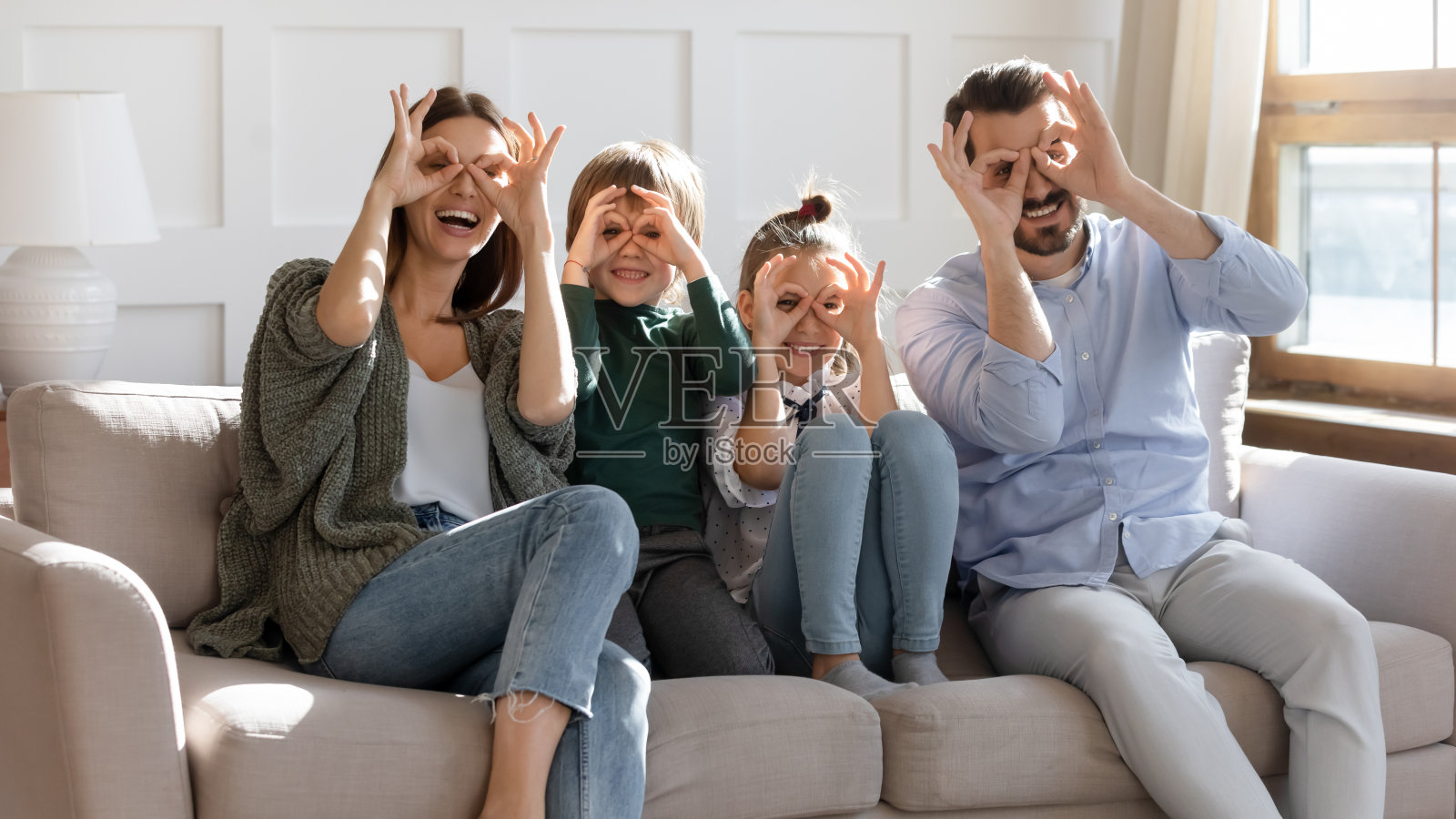 大喜的一家人用手指制作望远镜。照片摄影图片