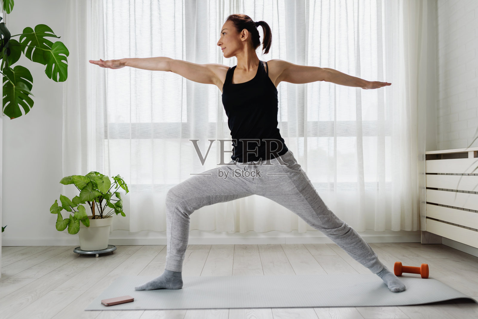 一个女人早上在家练瑜伽，在大窗户旁边照片摄影图片