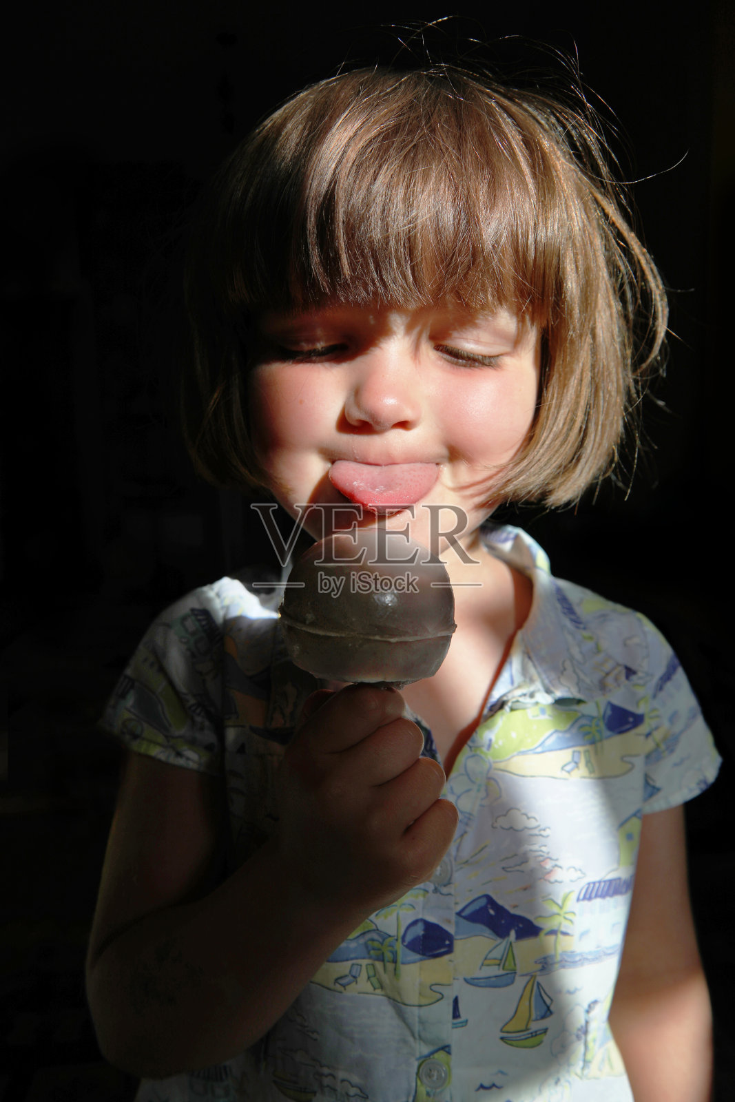 小女孩在舔她的冰淇淋。照片摄影图片