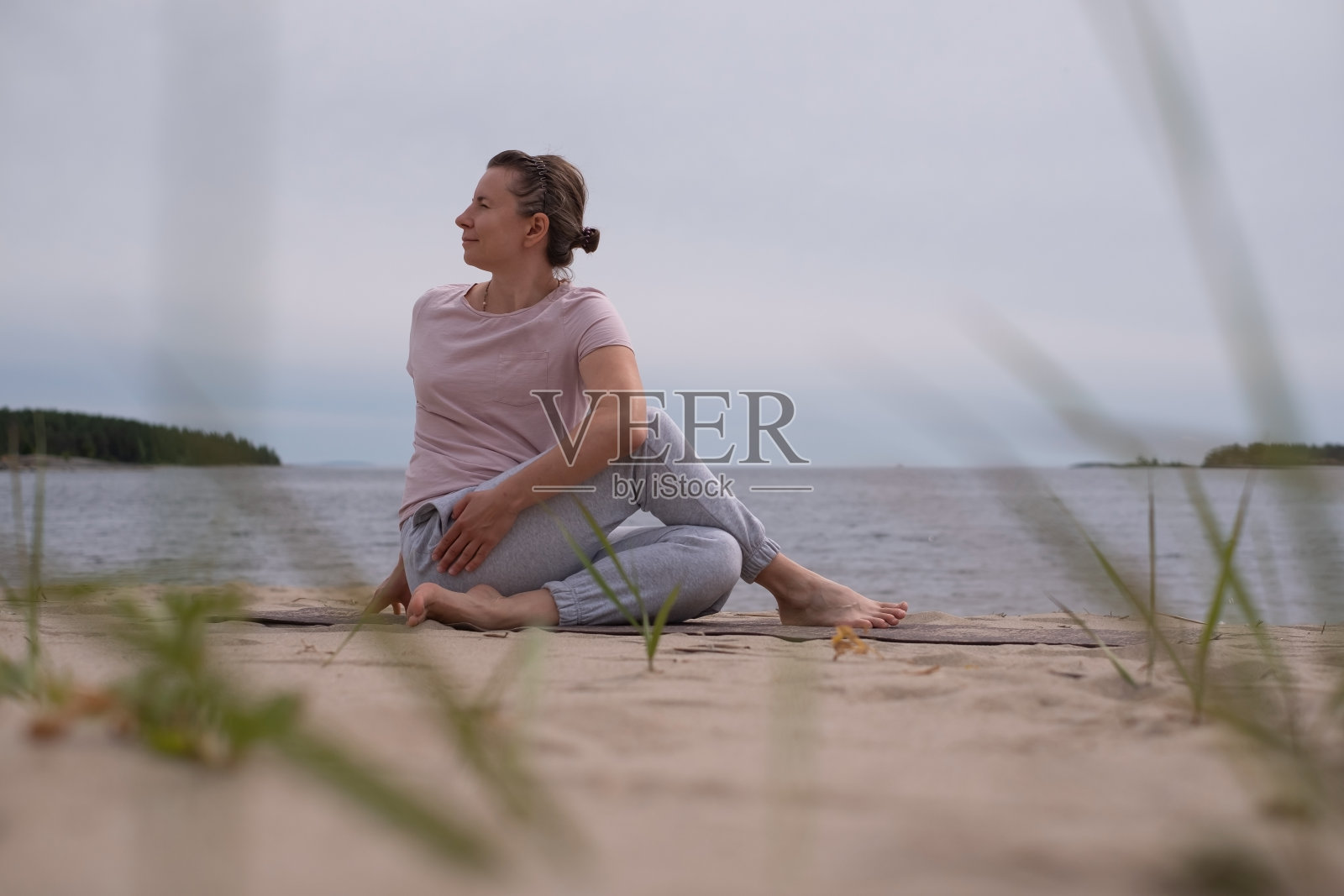 在沙滩上练习瑜伽的女人。照片摄影图片