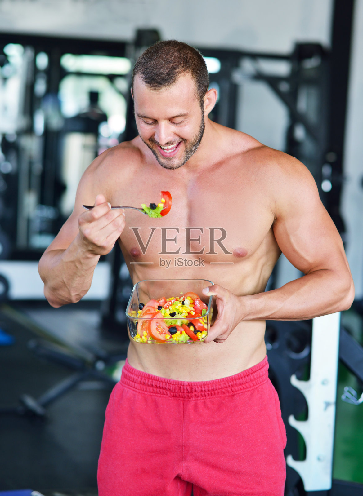 体格强健的运动员吃着健康的沙拉。照片摄影图片