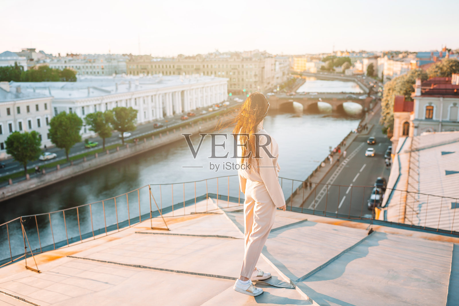 女人在屋顶上享受美丽的日落在圣彼得堡在俄罗斯照片摄影图片