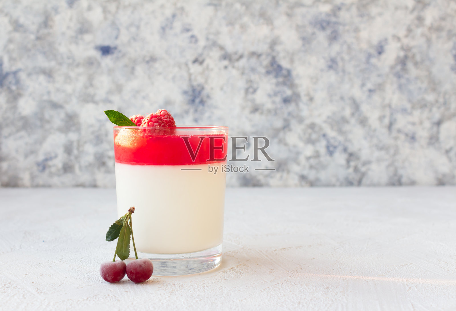 杯装意大利意式干酪甜点，饰以冰冻的覆盆子和樱桃。照片摄影图片