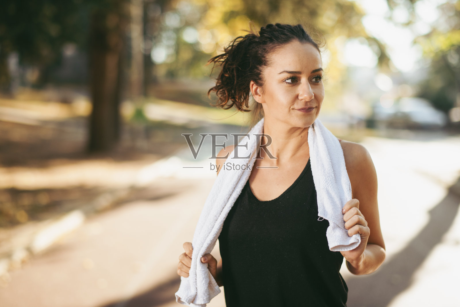 用毛巾在户外跑道上跑步的女运动员照片摄影图片