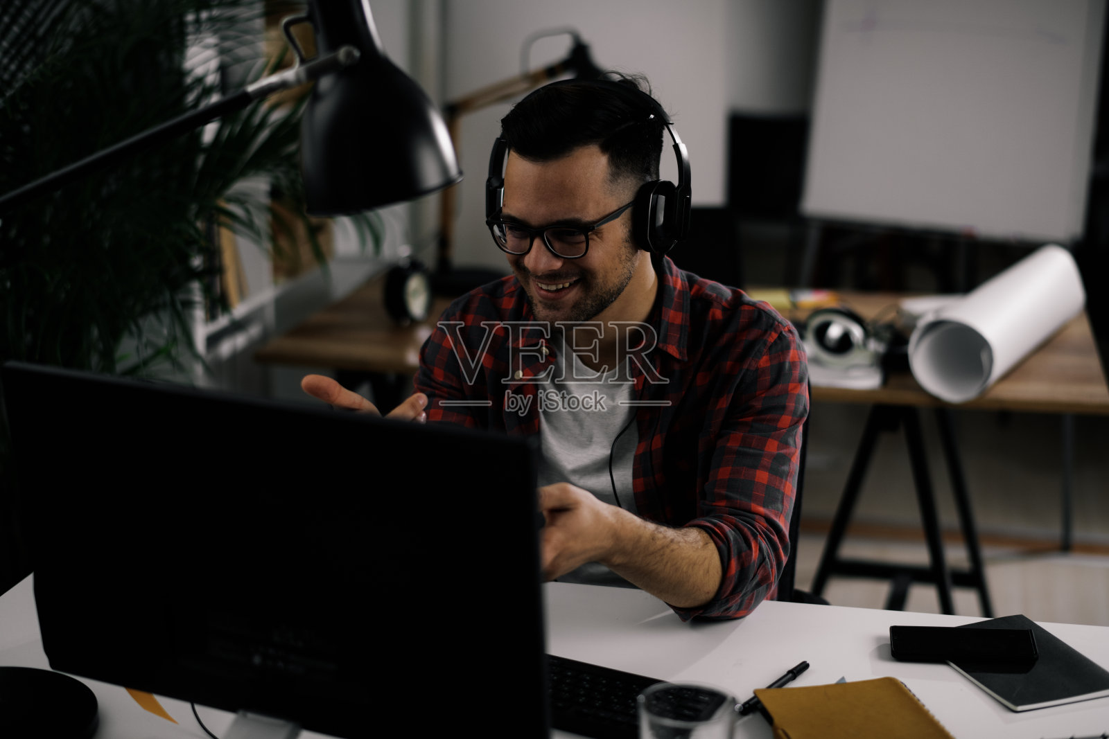 英俊的商人一边听着音乐一边在办公室工作。照片摄影图片