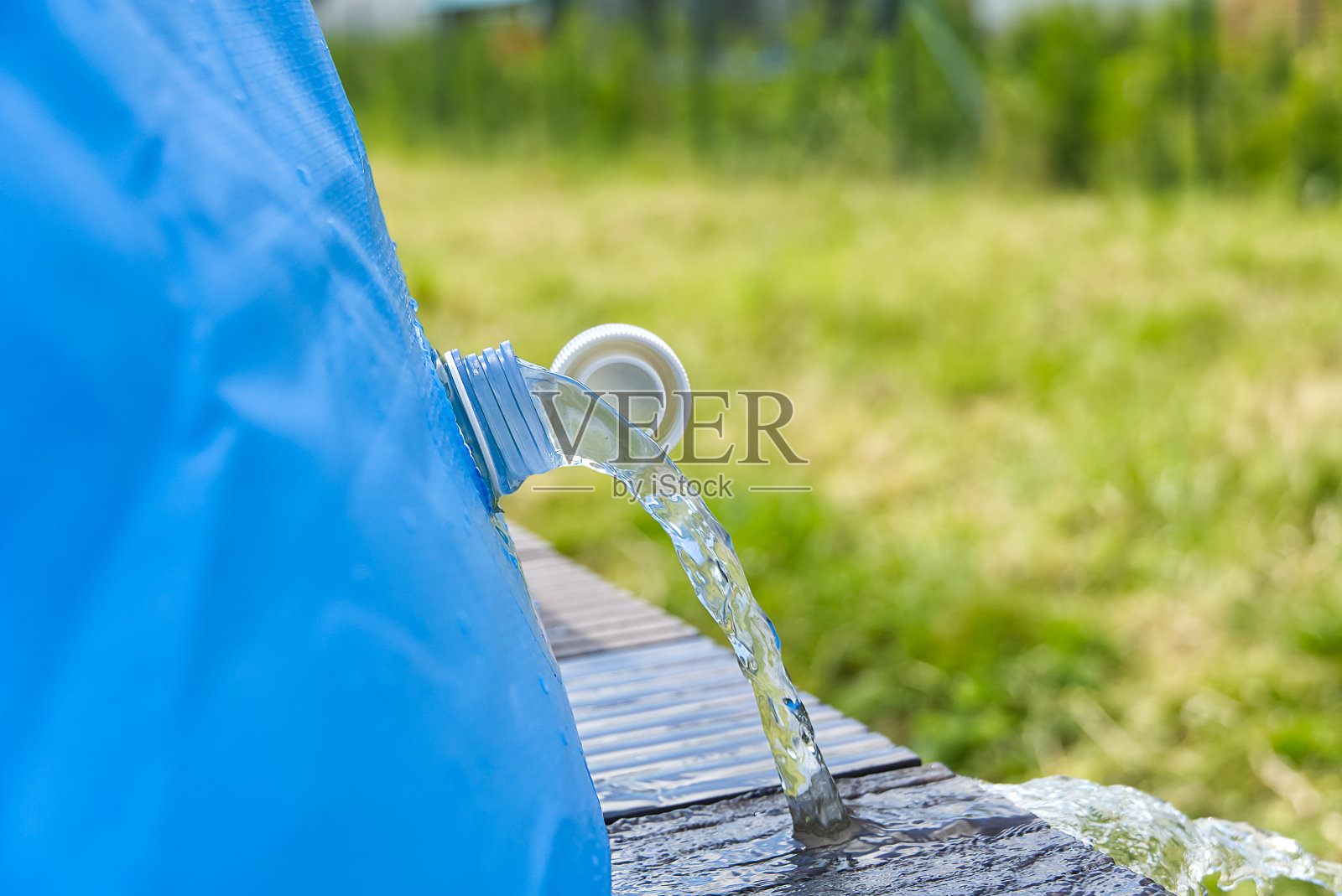 充气游泳池的排水从水管中流出的水。阳台上夏季水池的水的变化。照片摄影图片