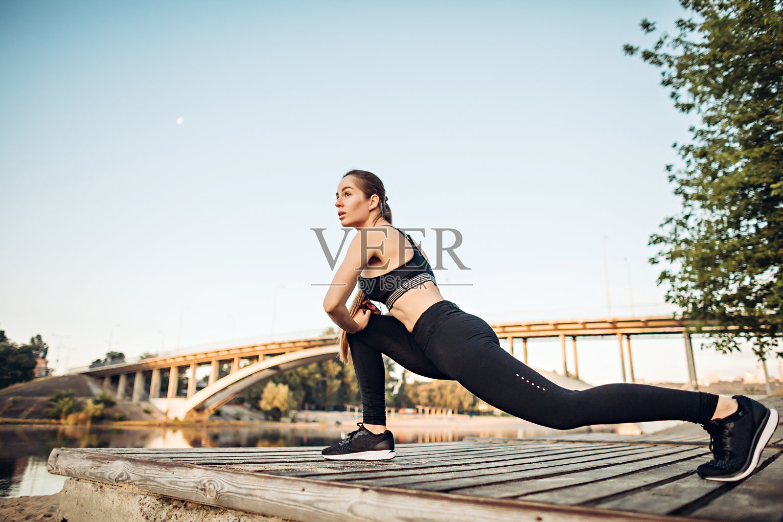 女孩在河边的木平台上做运动照片摄影图片