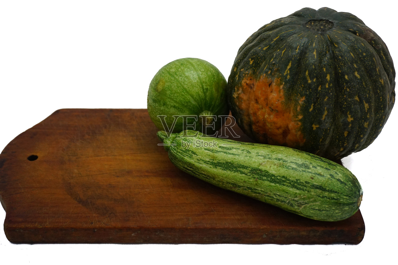 整只绿色的圆鞋紧挨着卡布蒂鞋和一只西葫芦，放在木板上，白色的背景上照片摄影图片