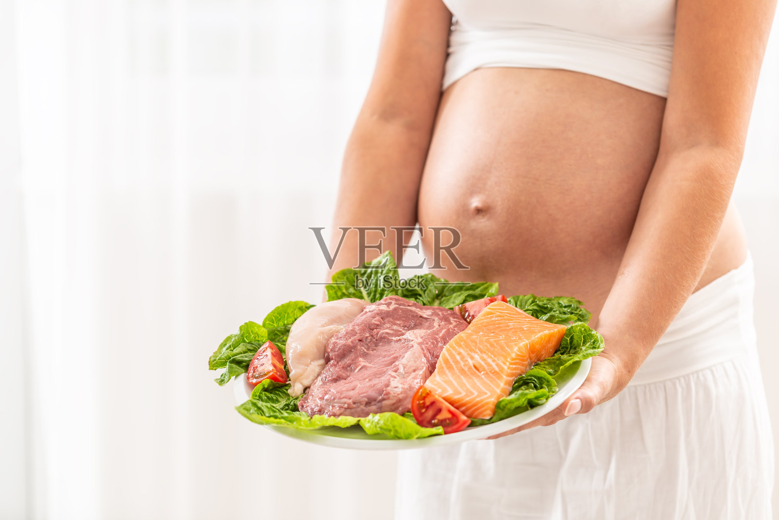 一盘新鲜的肉，鸡肉，牛肉和鱼，三文鱼沙拉叶子由一个孕妇。照片摄影图片