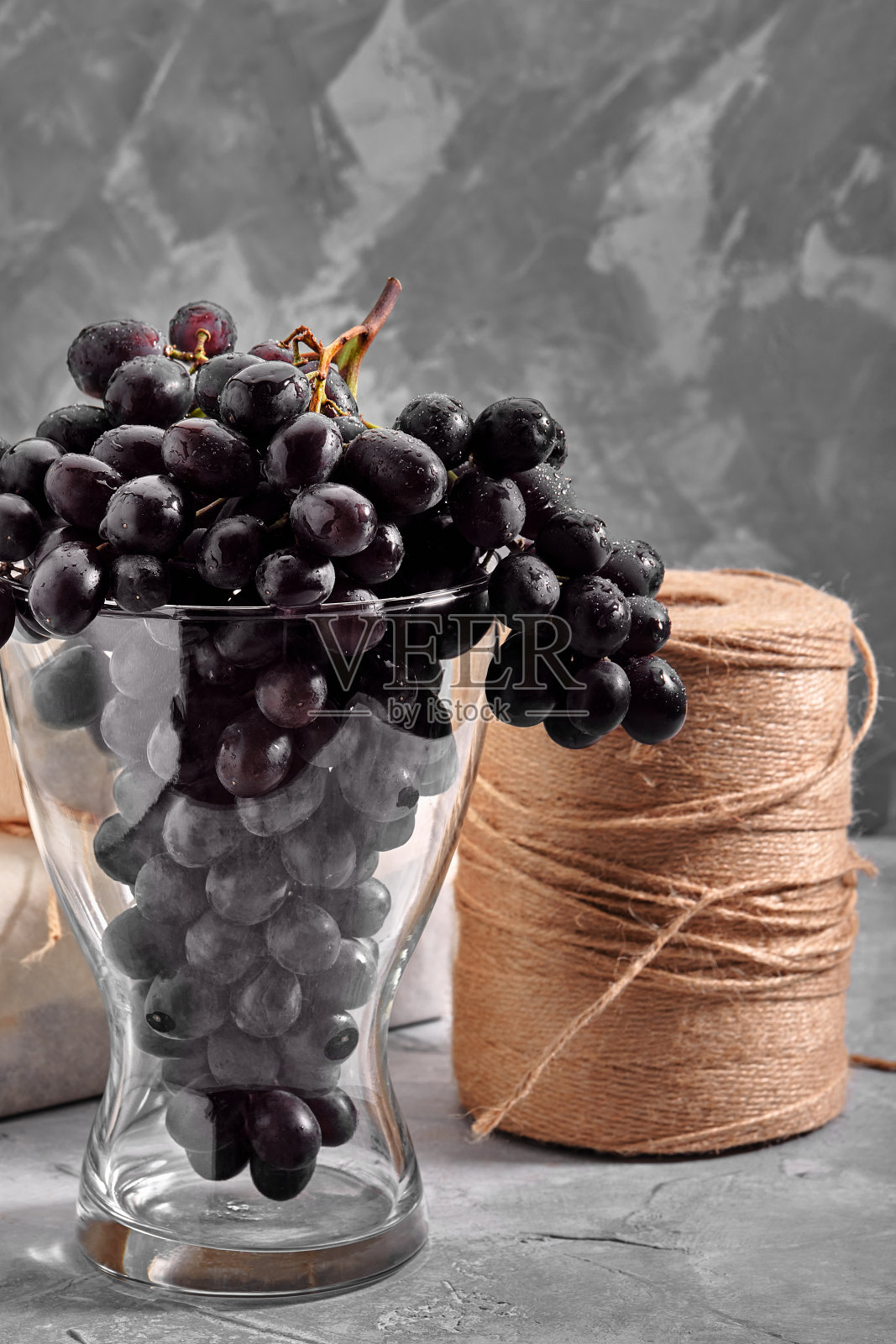 混凝土表面上挂着一串串新鲜成熟的黑葡萄。红酒的葡萄。食物的静物。大自然。秋天的收获。素食营养。酒庄照片摄影图片