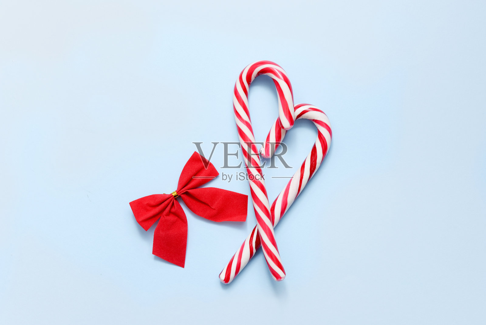 两根心形拐杖糖，红色蝴蝶结，蓝色背景，复制空间照片摄影图片
