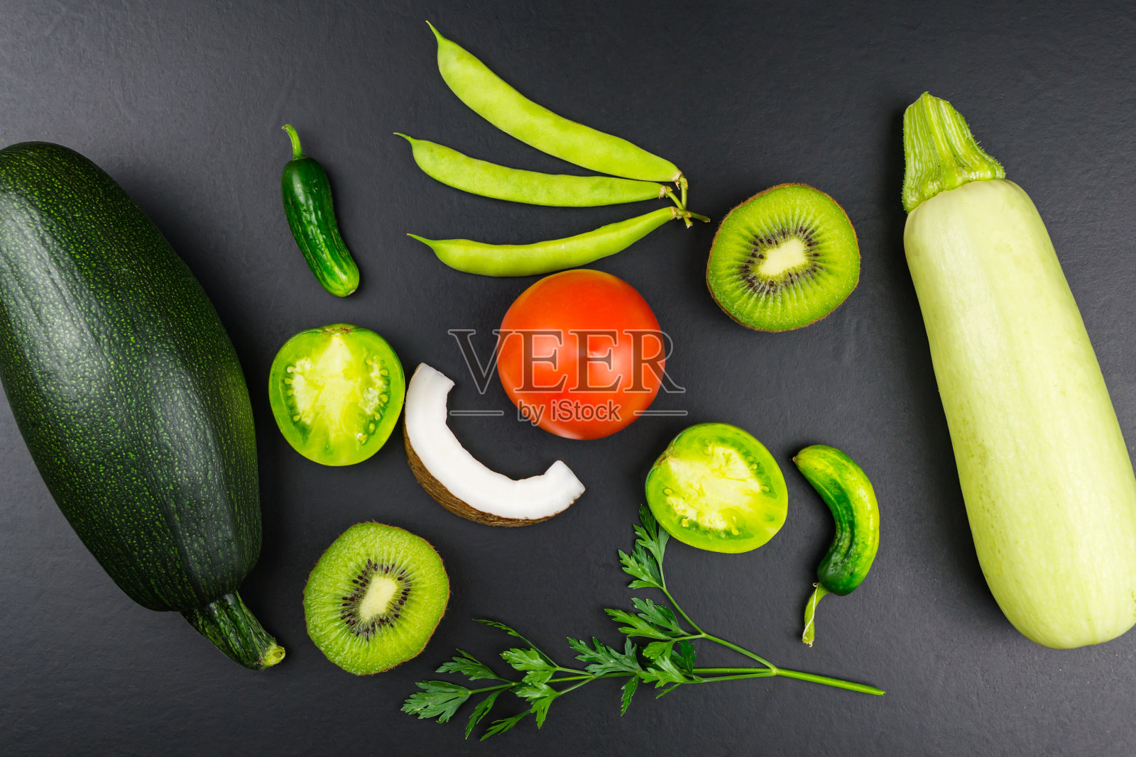 俯视图西葫芦，辣椒，辣椒，青豆，黄瓜，西红柿，猕猴桃，芒果，梨，苹果，欧芹。黑色背景照片摄影图片