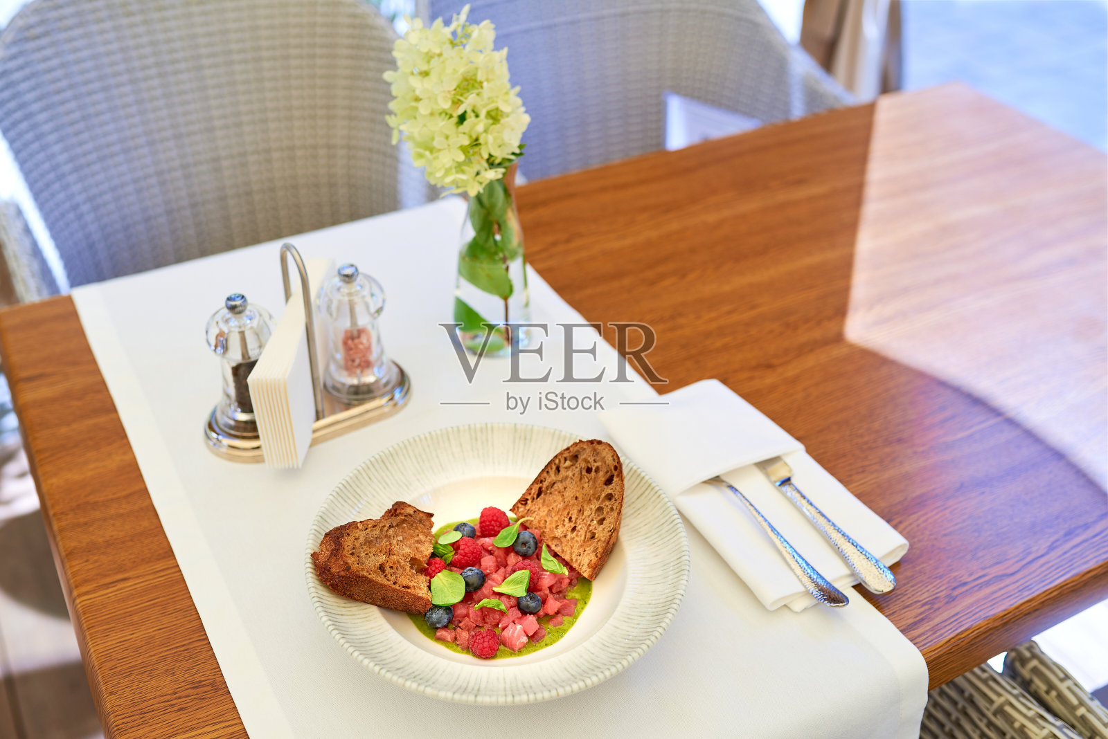 金枪鱼鞑靼与覆盆子和蓝莓在一个白色的盘子。照片摄影图片