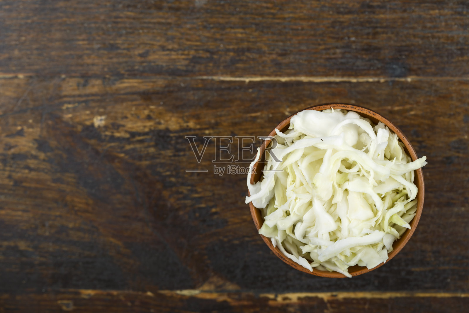 木背景上的碗里切碎的卷心菜。蔬菜、配料及主食。照片摄影图片