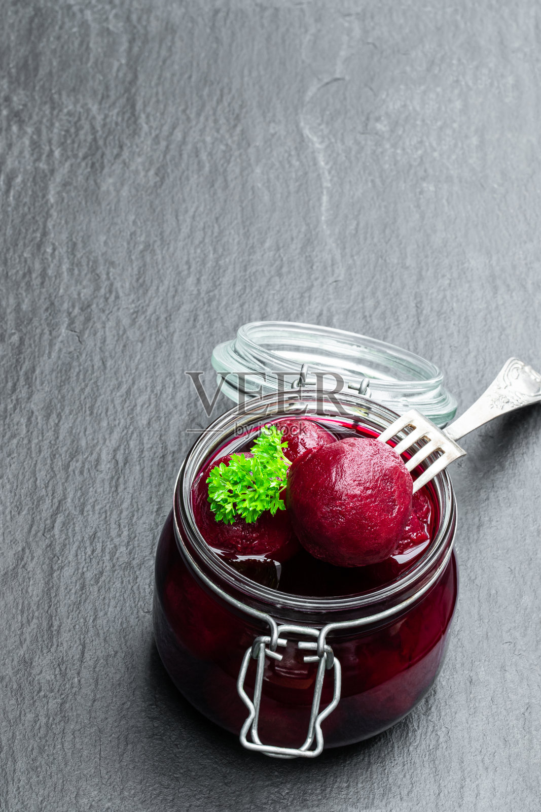 自制的腌小甜菜根在玻璃保存罐在黑色的石头背景照片摄影图片