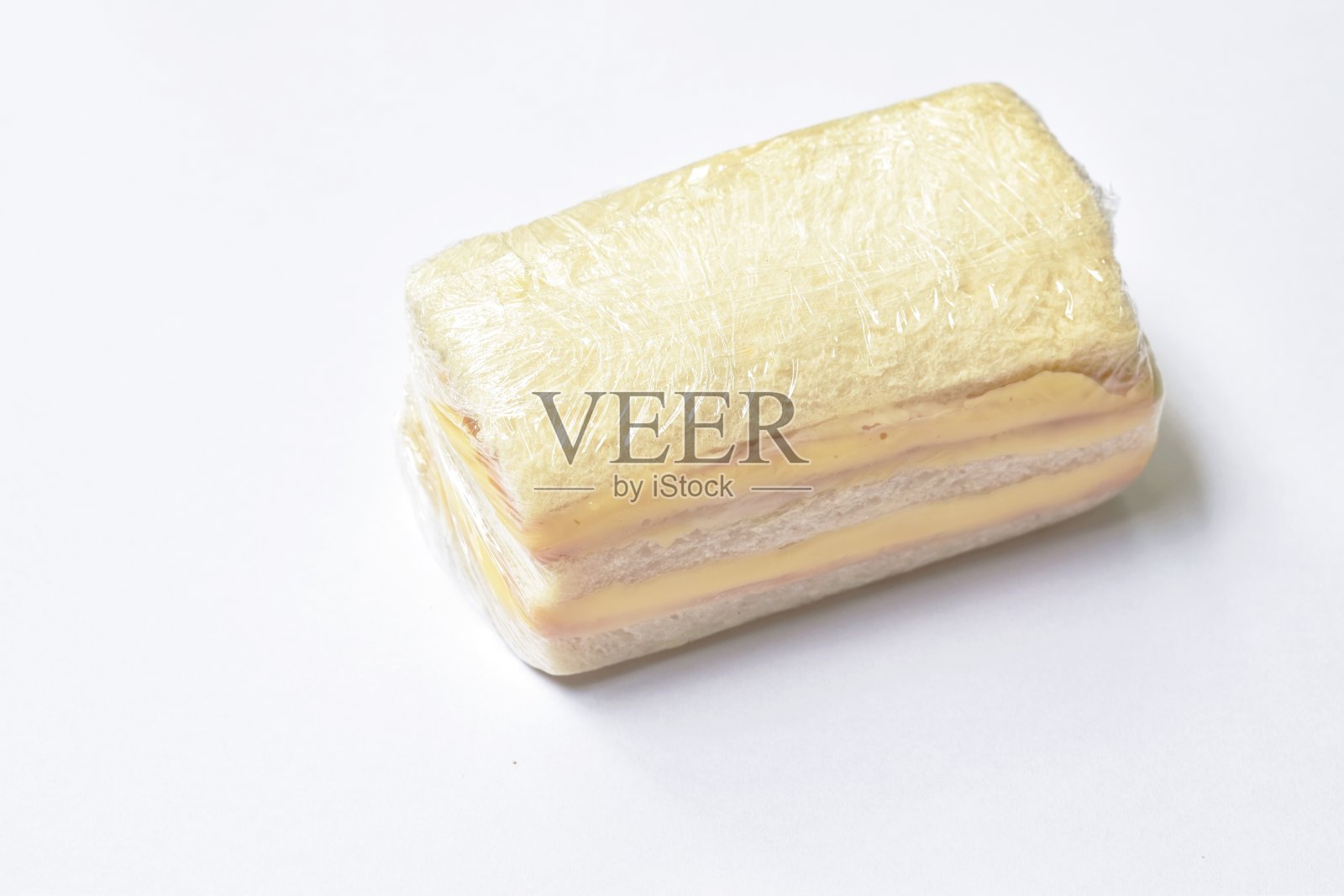 三明治填充火腿和奶酪包装在透明塑料在白色的背景照片摄影图片