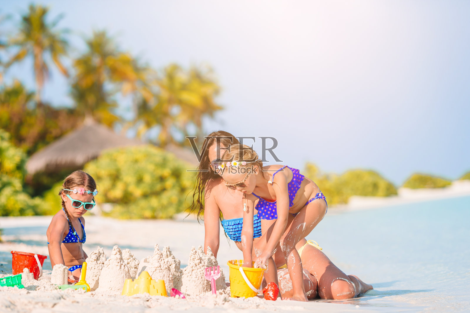 妈妈和小女儿们在热带海滩上做沙堡照片摄影图片