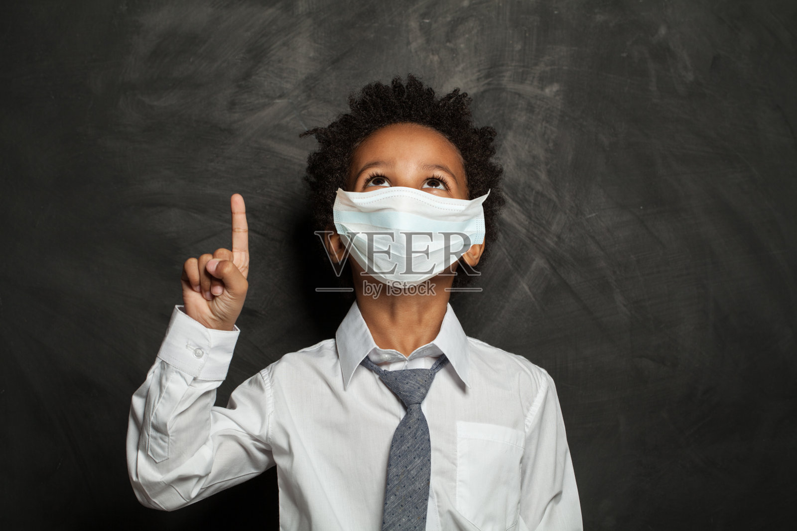 黑色男孩在医疗防护口罩指向黑板背景照片摄影图片