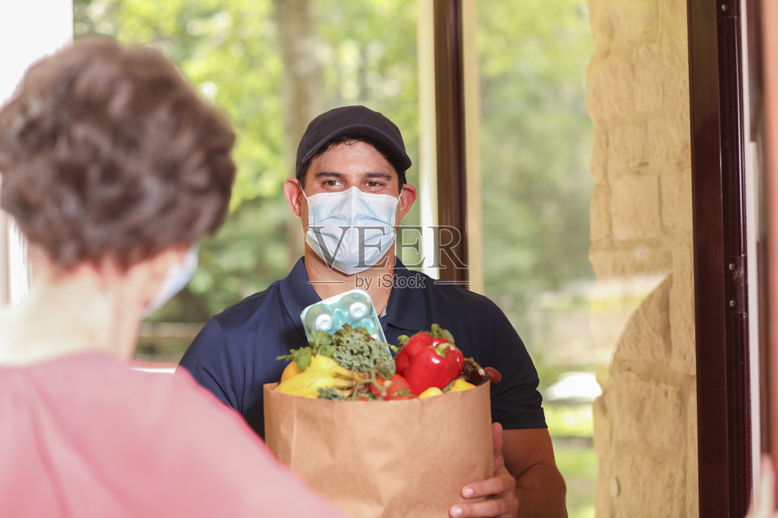 冠状病毒:一名男子在家为女上司送杂货。照片摄影图片