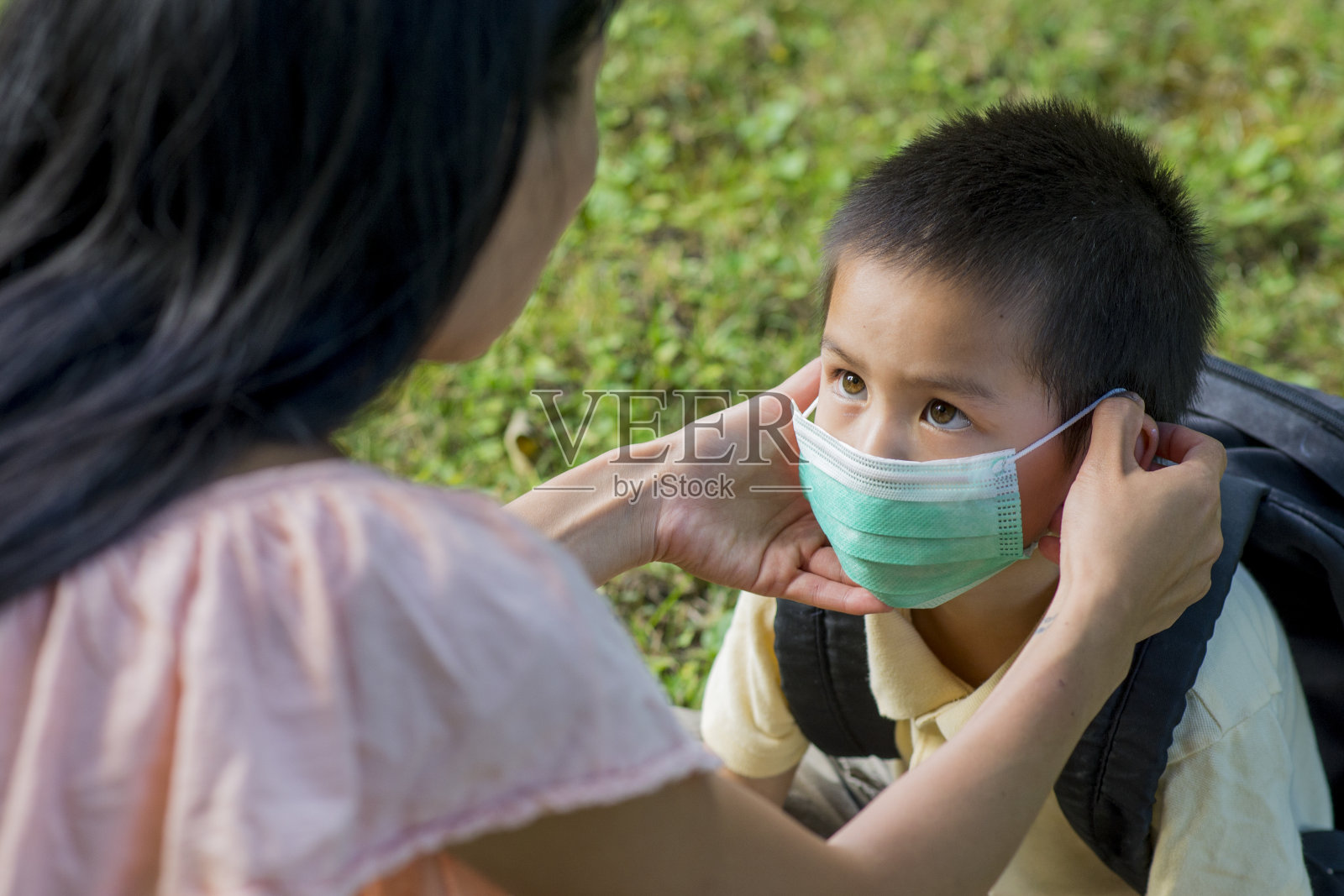 妈妈给上学的儿子戴上口罩照片摄影图片