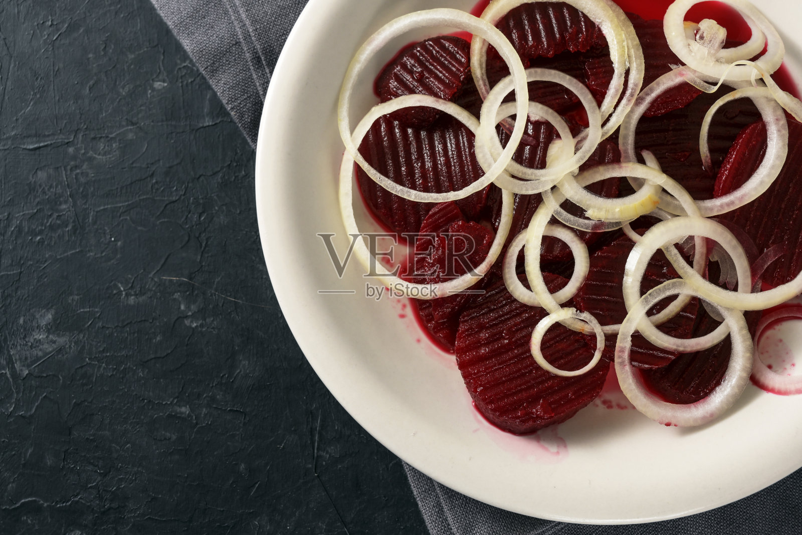 甜菜根片和洋葱圈放在一个白色的盘子和一个黑色的石板背景，拷贝空间，高角度从上面看照片摄影图片