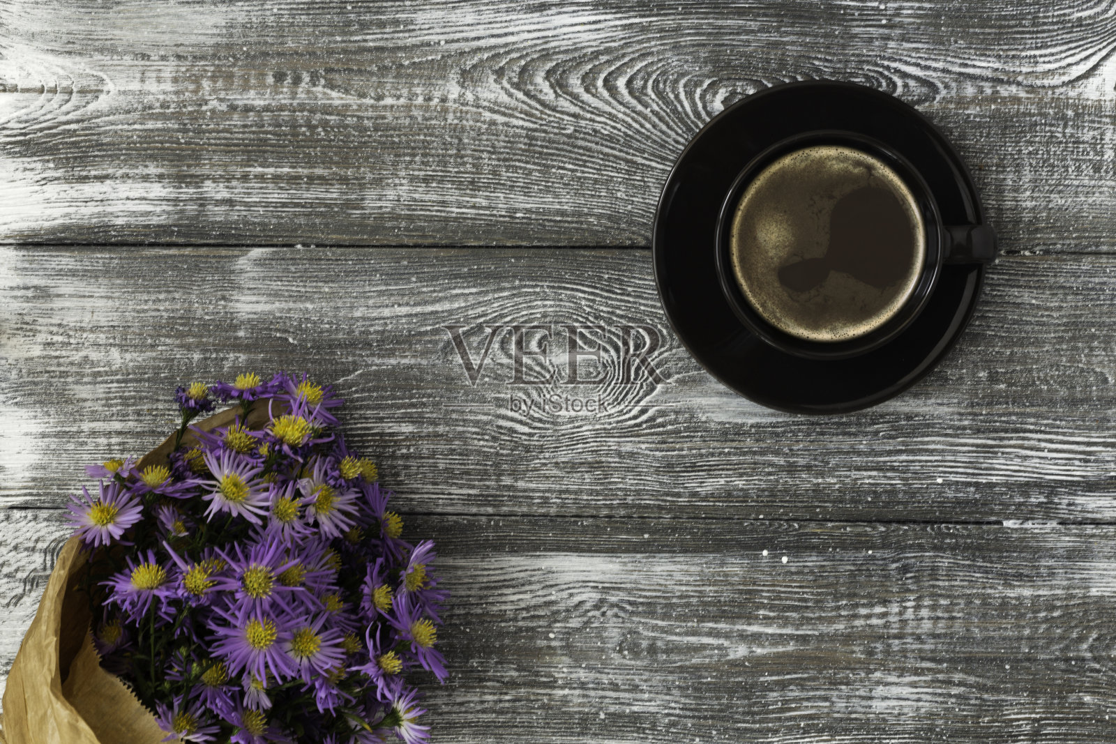 灰色的桌子上放着一杯咖啡，一束用牛皮纸包着的花。平铺粉彩造型。为文本复制空间。照片摄影图片