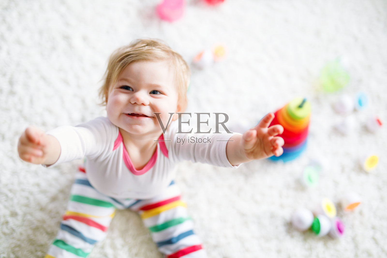 可爱可爱的小女孩在家里或托儿所玩益智玩具。快乐健康的孩子有乐趣的彩色木制彩虹男孩玩具金字塔。孩子学习不同的技能。照片摄影图片