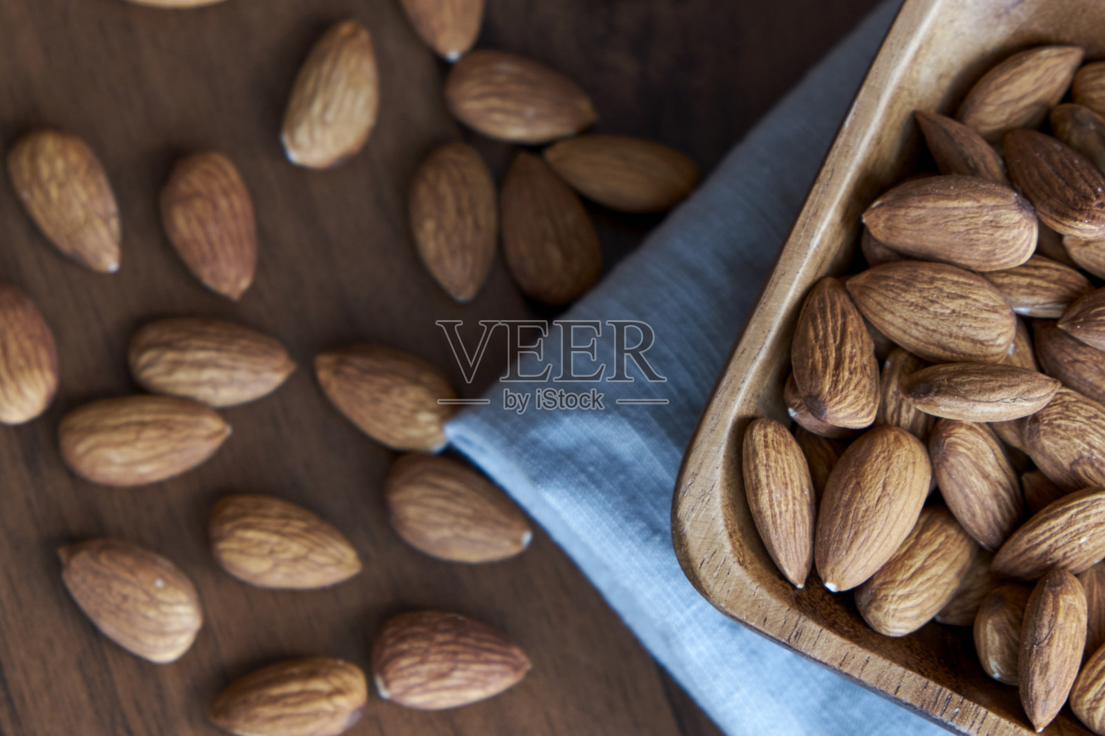 杏仁装在小木碗里。杏仁随意地摆放在黑暗的桌子上。排碗杏仁坚果，俯视图。去皮杏仁图案照片摄影图片