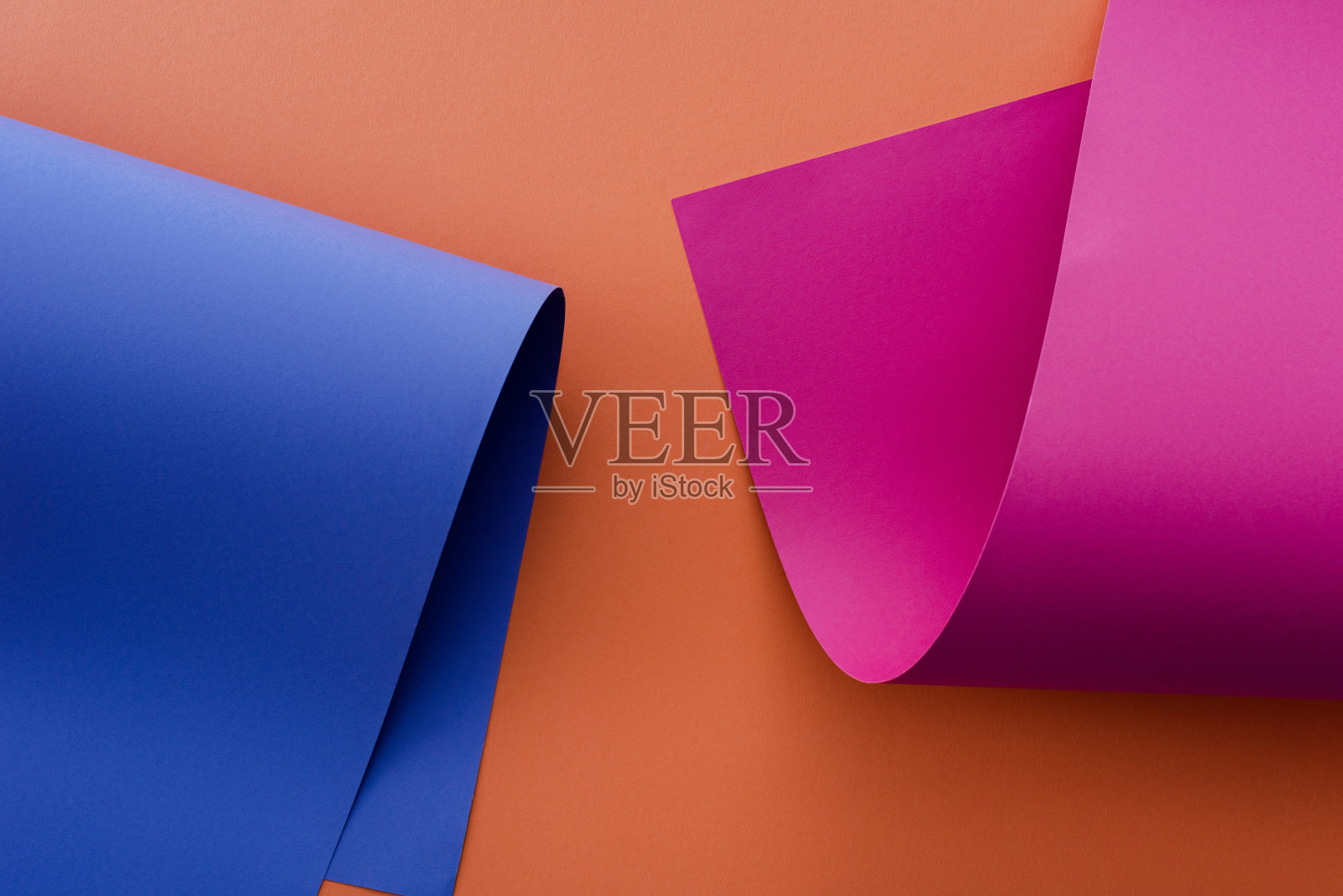蓝色和粉红色的彩色纸在橙色的背景照片摄影图片