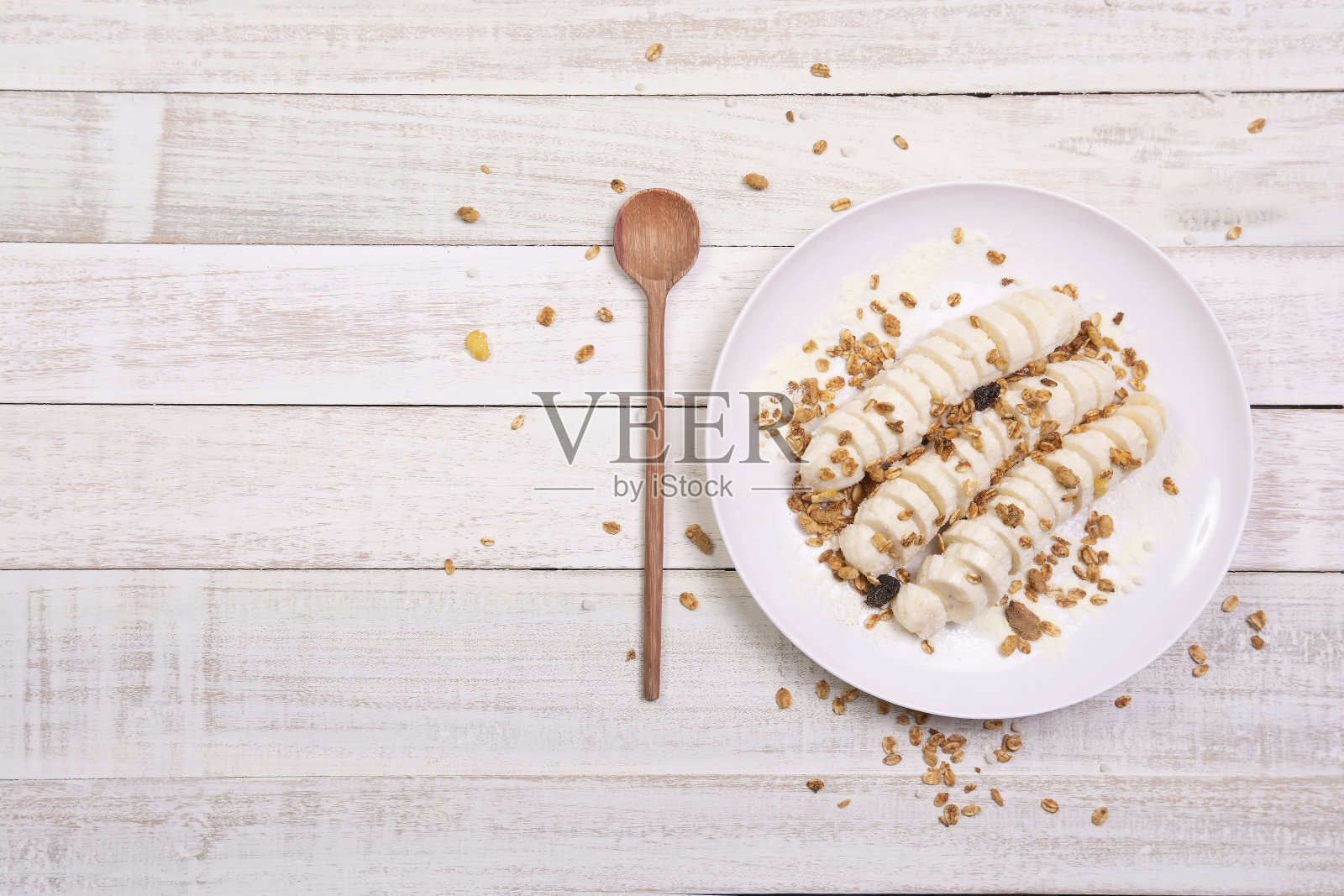 香蕉片和格兰诺拉麦片在盘子上白色的木材背景复制空间。健康的天然维生素零食。俯视图，平面布局照片摄影图片