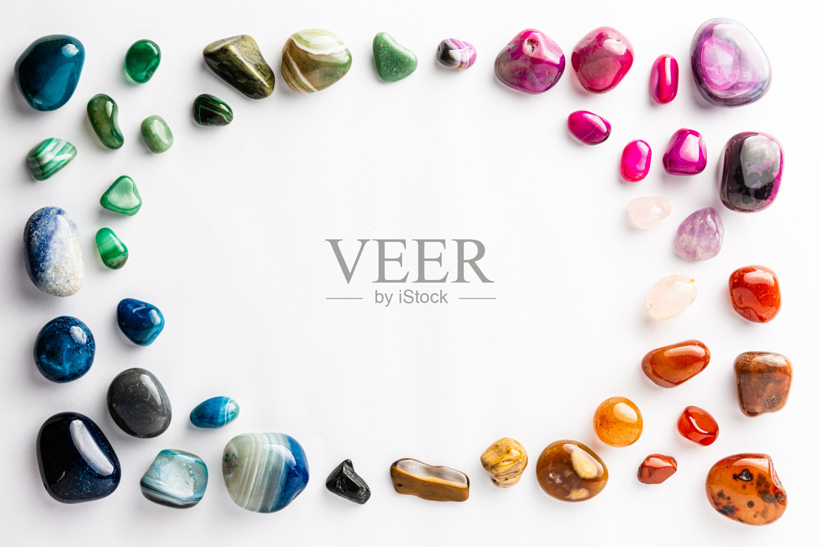 五颜六色的半宝石整齐地排列在白色背景上，中间有一个圆形的空地照片摄影图片