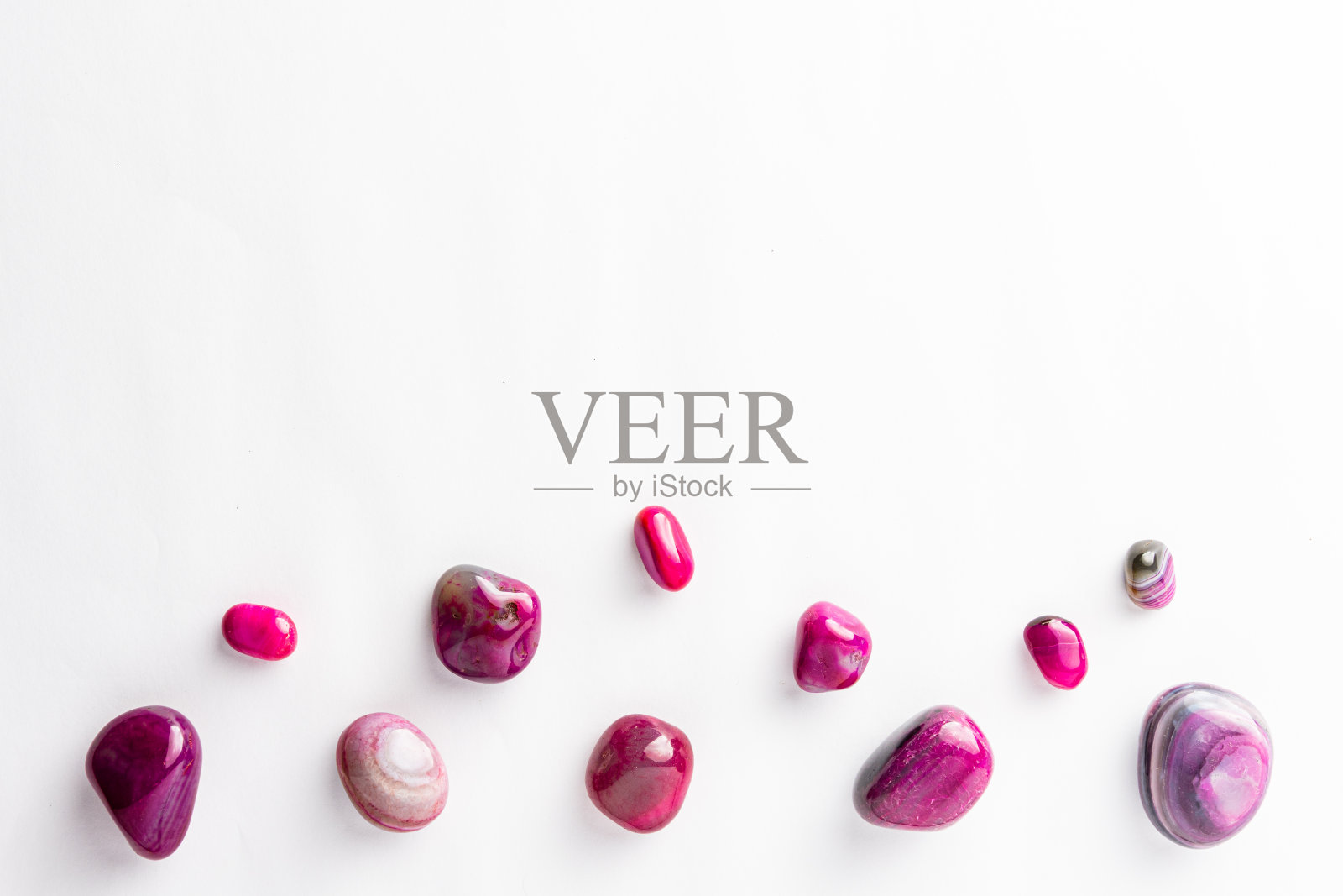 粉红色的半宝石整齐地排列着，上面有一块空白的空间，背景是白色照片摄影图片