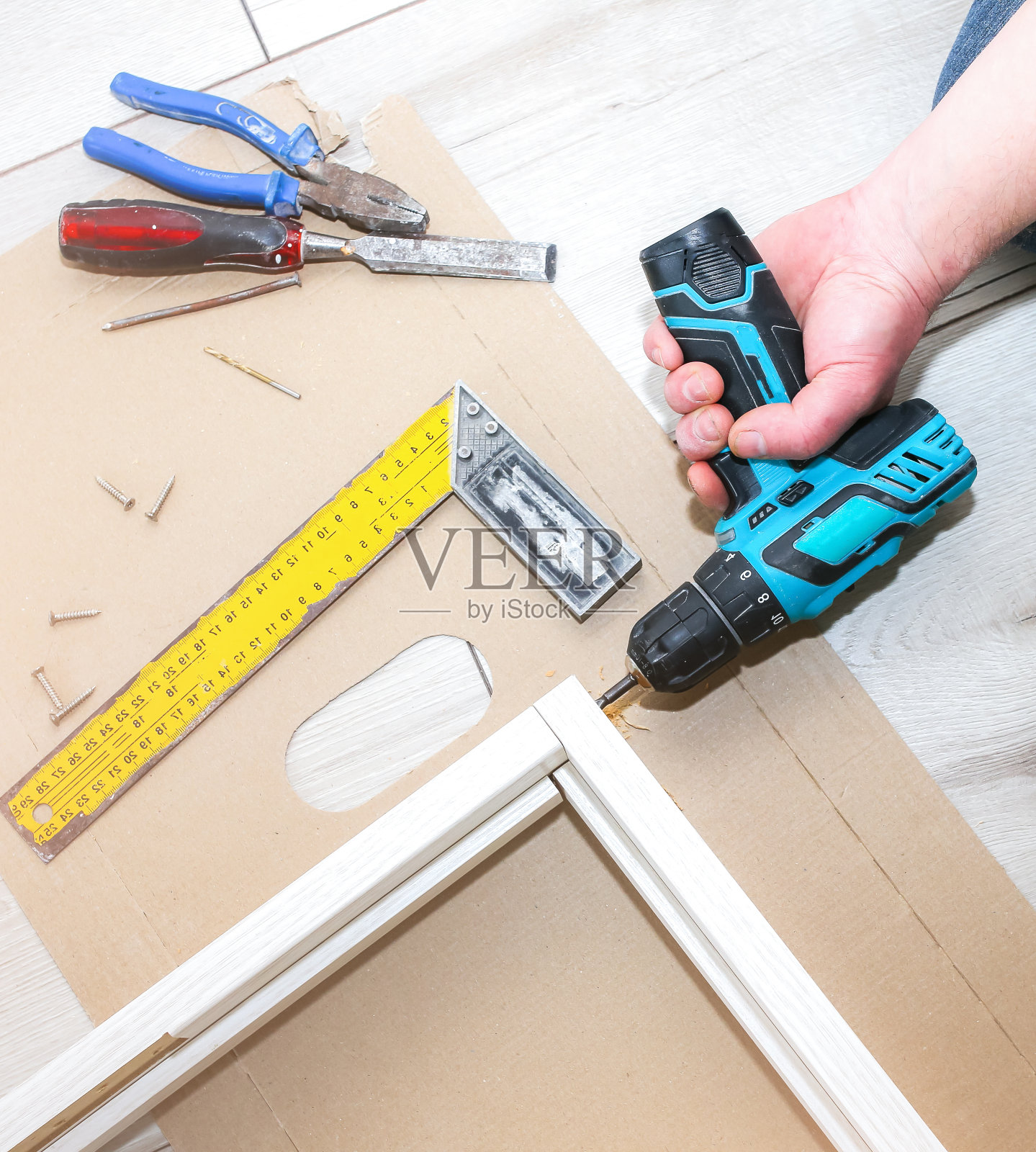 有人在安装门。木匠手里拿着钻头。修复工作。公寓的维护。照片摄影图片